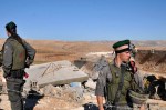 Israeli soldiers stand guard as a bulldozer knocks down the wall of a house in the village of&nbsp;Yatta