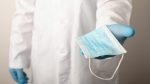 Studio photo of a doctor giving disposal medical mask to a&nbsp;patient