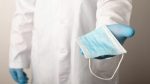 Studio photo of a doctor giving disposal medical mask to a&nbsp;patient